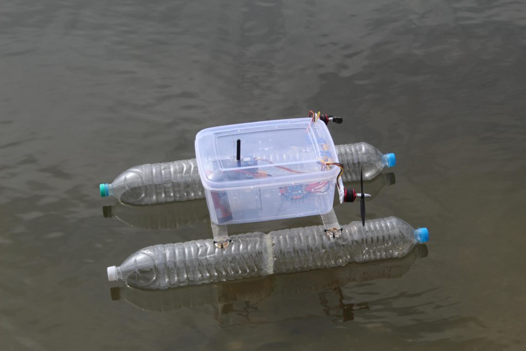 Small-scale autonomous boat made out of recycled water bottles and a  Tupperware container