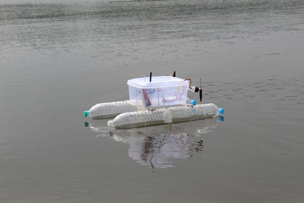 Small-scale autonomous boat made out of recycled water bottles and a  Tupperware container