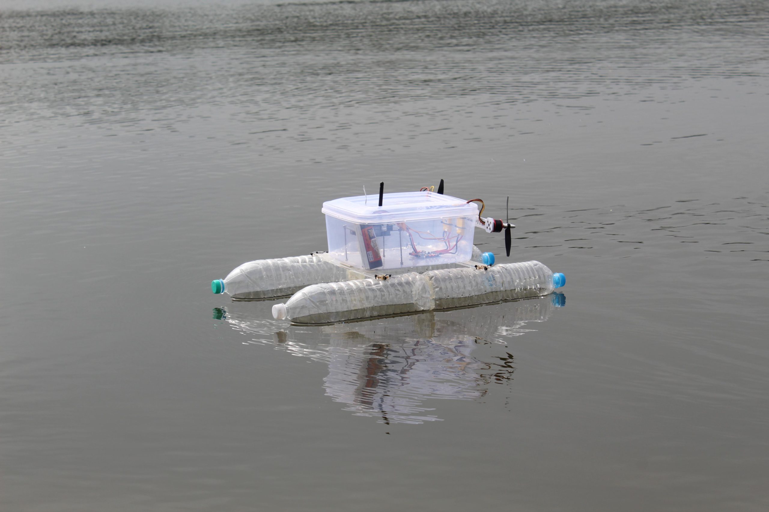 Small-scale autonomous boat made out of recycled water bottles and a Tupperware container